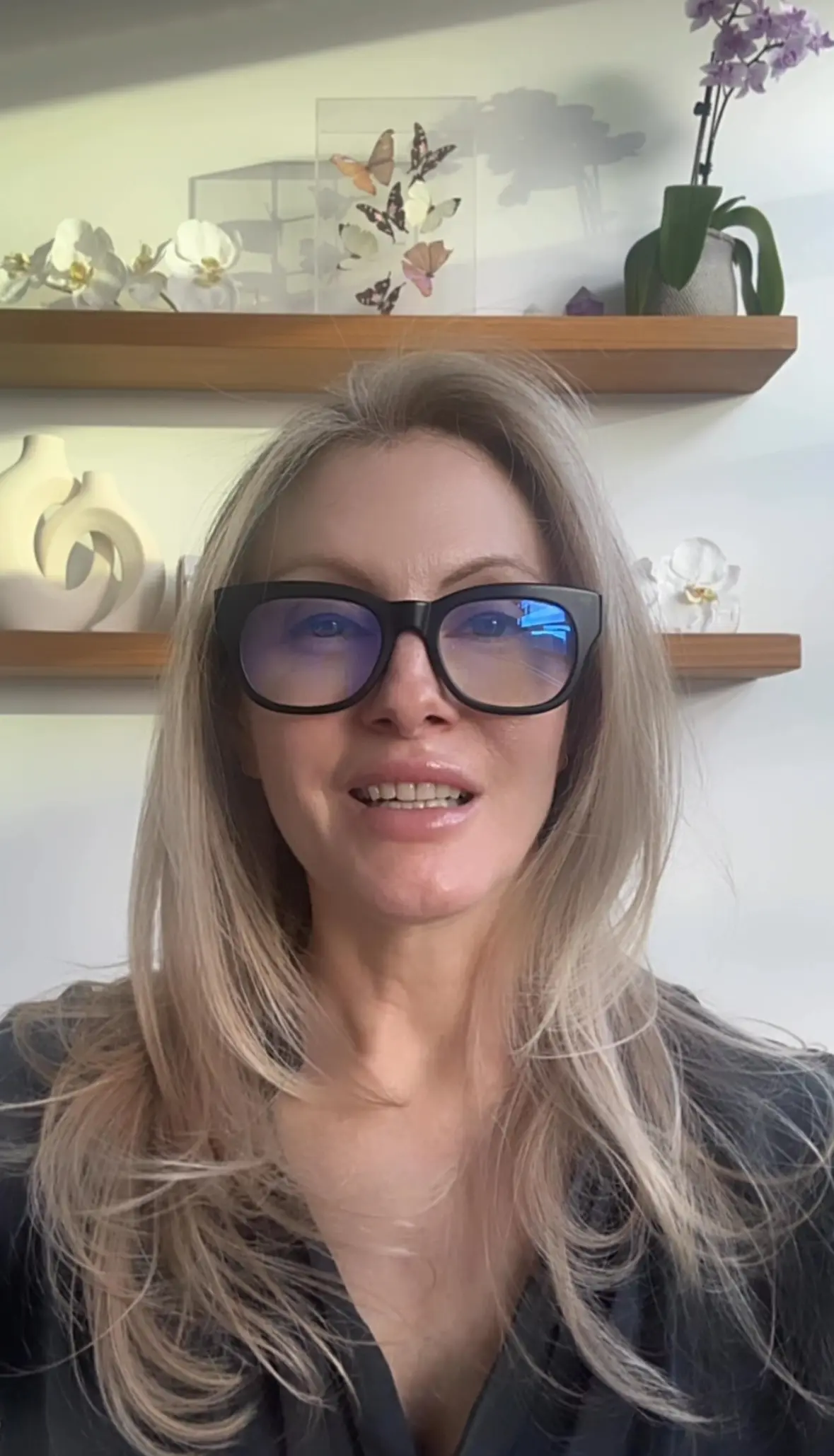 A woman with long blonde hair wearing glasses.